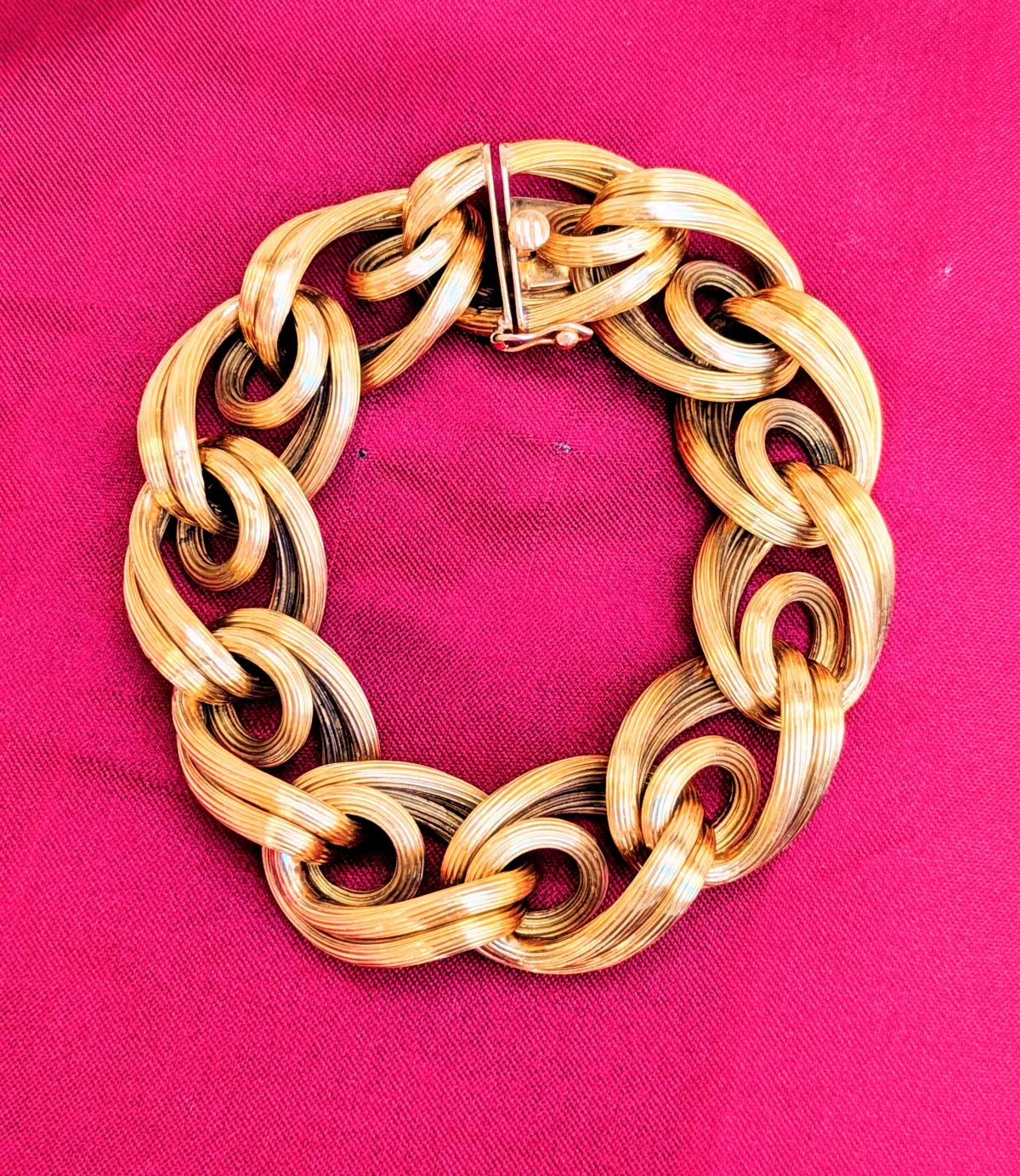 Gold bracelet photographed on a rich magenta background
